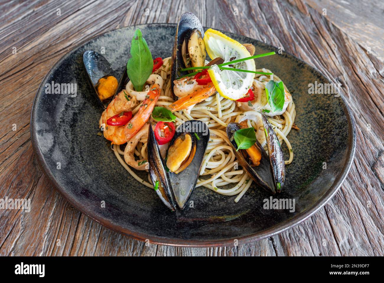 Fisch und Meeresfrüchte, mediterrane Küche. Spaghetti mit Tintenfisch, Austern, Garnelen und Kräutern. Muscheln Stockfoto