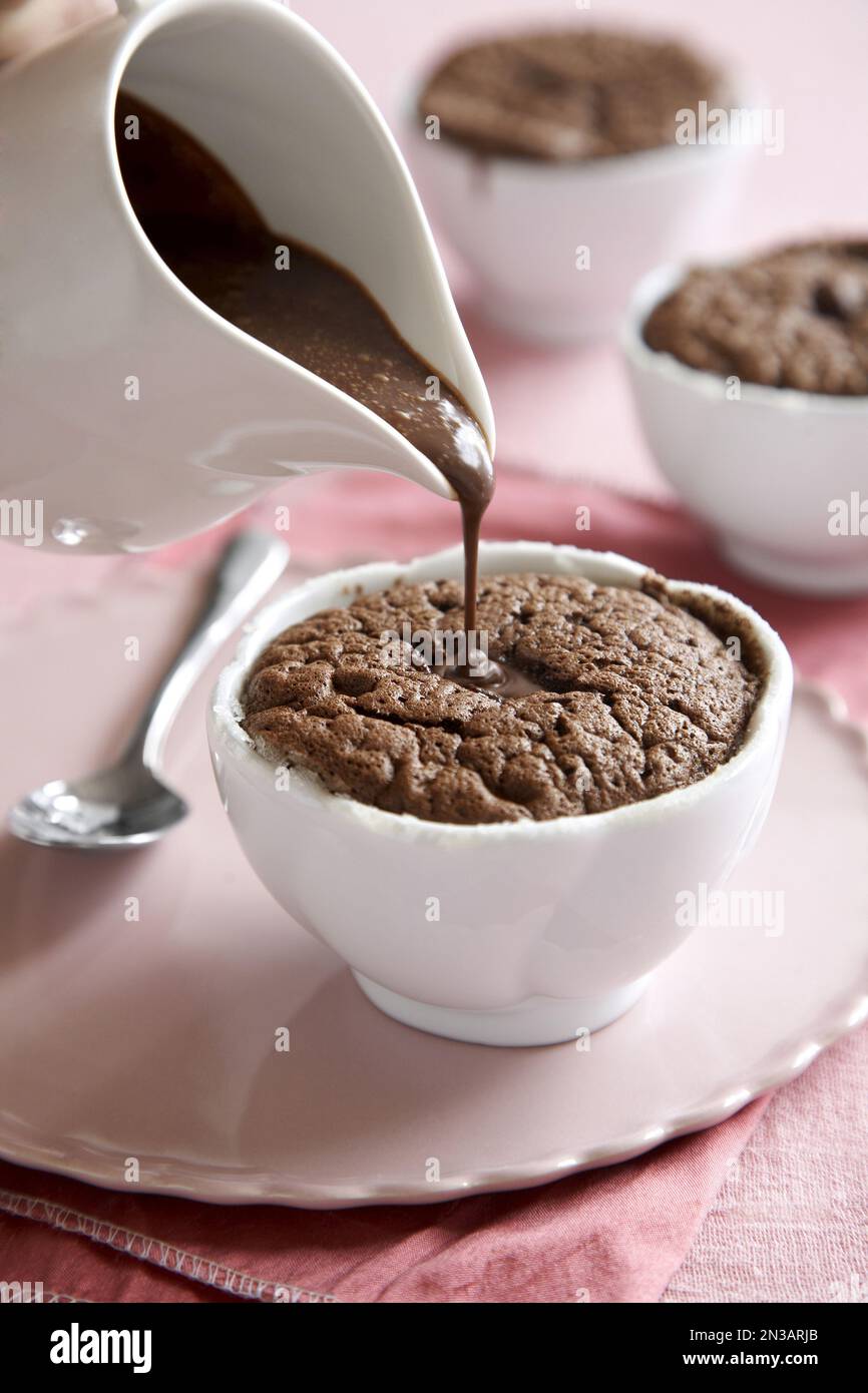 Individuelles Schokoladensouffle mit Schokoladensoße oben auf pinkfarbenem Hintergrund Stockfoto