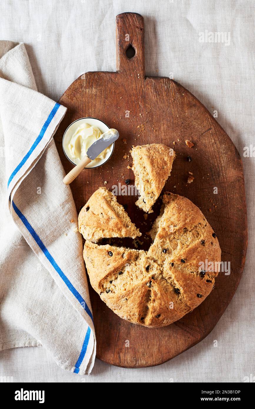 Irisches Limonadenbrot mit Johannisbeeren und eine kleine Butterschale auf einem Holzbrett Stockfoto