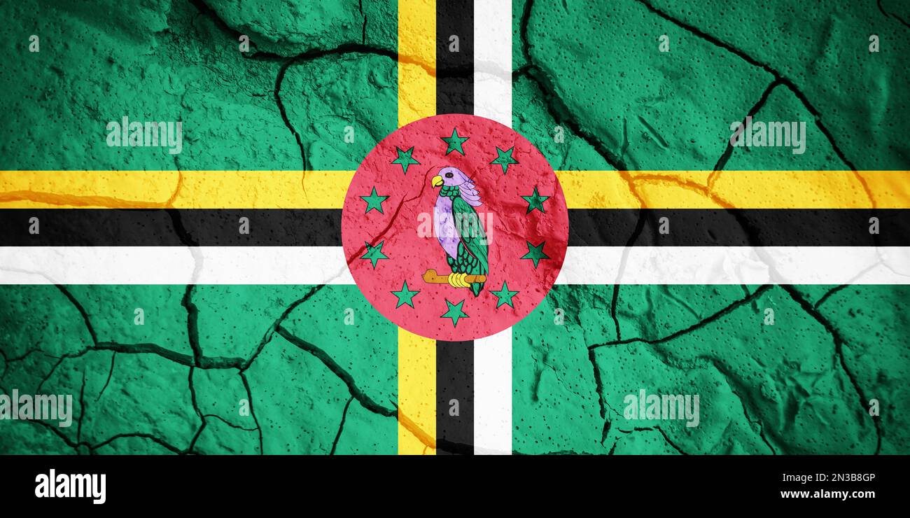 Flagge Dominicas. Dominica-Symbol. Flagge auf dem Hintergrund von trockener, gerissener Erde. Dominica-Flagge mit Dürrekonzept Stockfoto