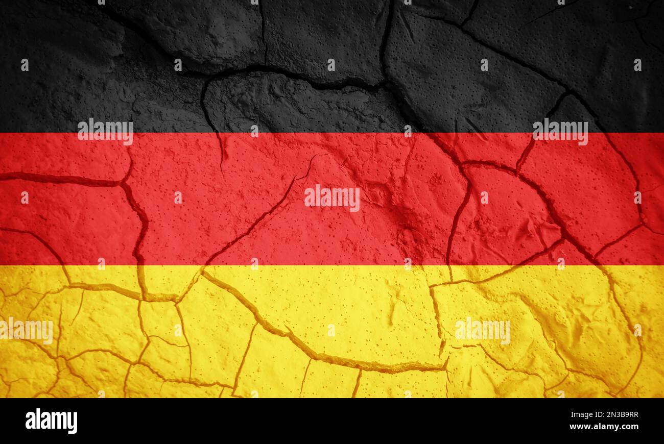 Flagge Deutschlands. Symbol für Deutschland. Flagge auf dem Hintergrund von trockener, gerissener Erde. Deutsche Flagge mit Dürrekonzept Stockfoto