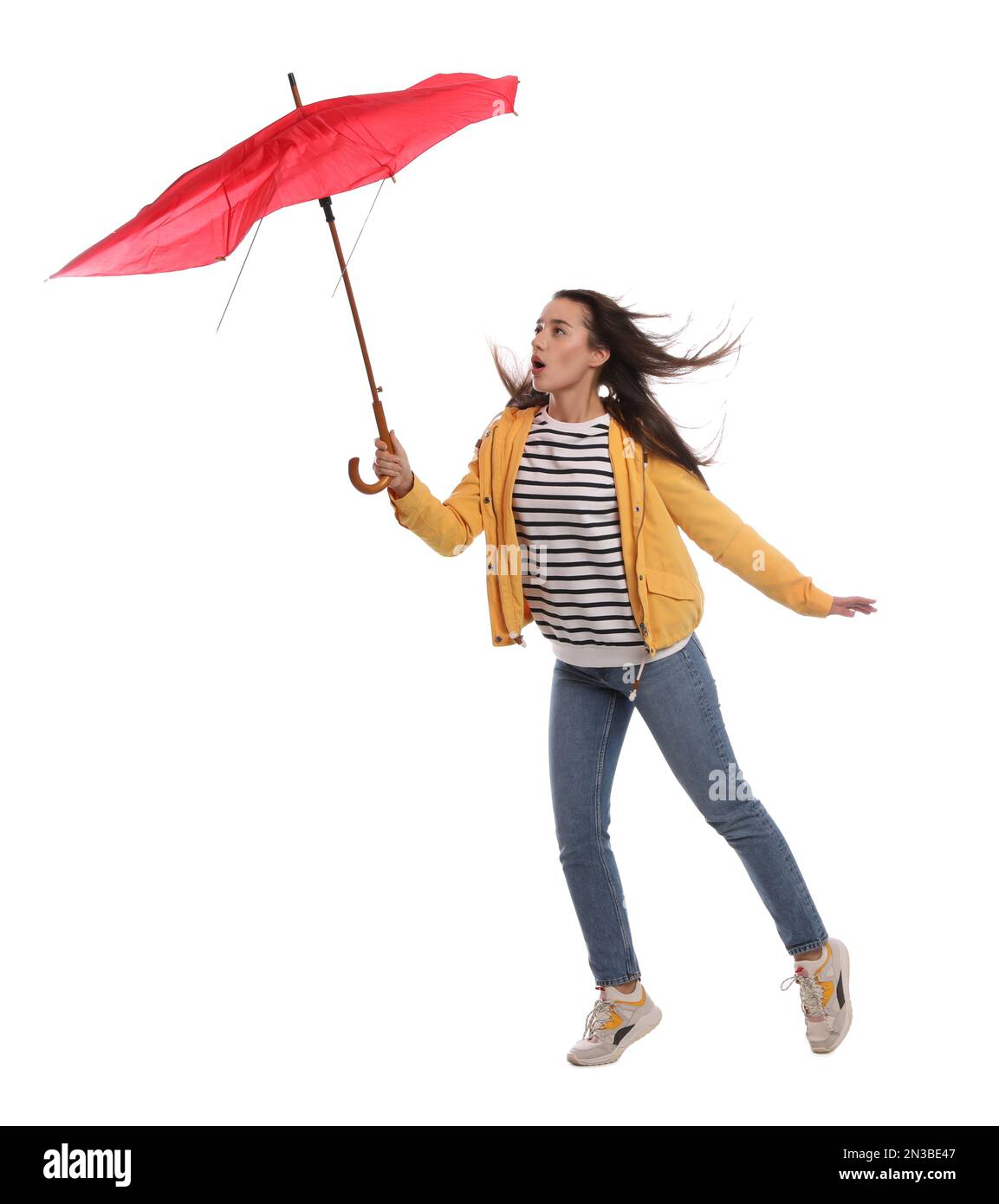 Emotionale Frau mit Regenschirm, die in Windböen auf weißem Hintergrund gefangen war Stockfoto