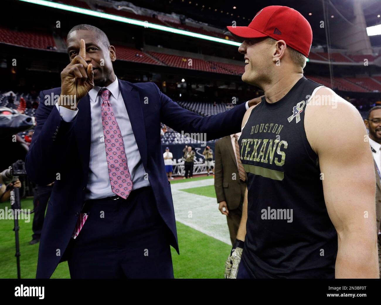 Former NBA player Dikembe Mutombo, left, does his signature finger wave with Houston Texans defensive end J.J. Watt before an NFL football game, against the Baltimore Ravens Sunday, Dec. 21, 2014, in Houston. (AP Photo/David J. Phillip) Stockfoto