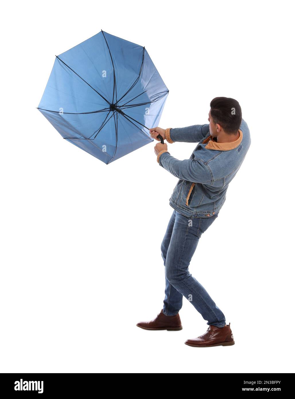 Ein Mann mit Regenschirm, der von Windböen auf weißem Hintergrund gefangen wurde Stockfoto