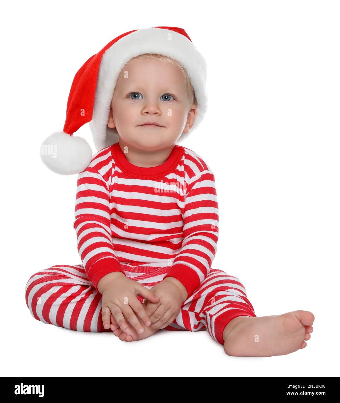 Süßes Baby mit Weihnachtsmannmütze und Weihnachtspyjama auf weißem Hintergrund Stockfoto