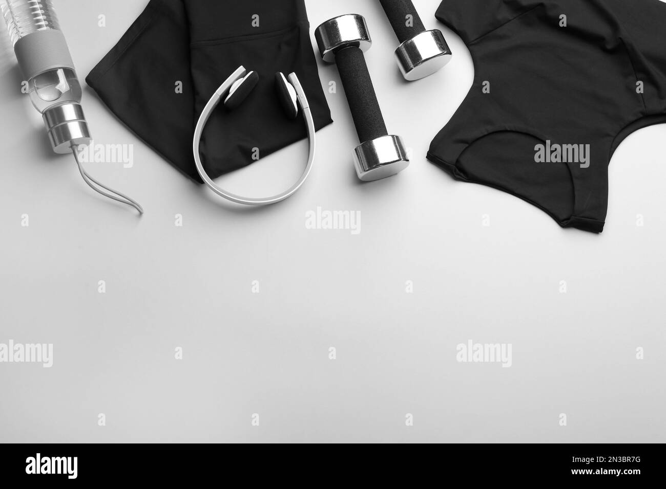 Flache Laienzusammensetzung mit Sportbekleidung und Ausrüstung auf hellgrauem Hintergrund, Platz für Text. Fitness-Workout Stockfoto