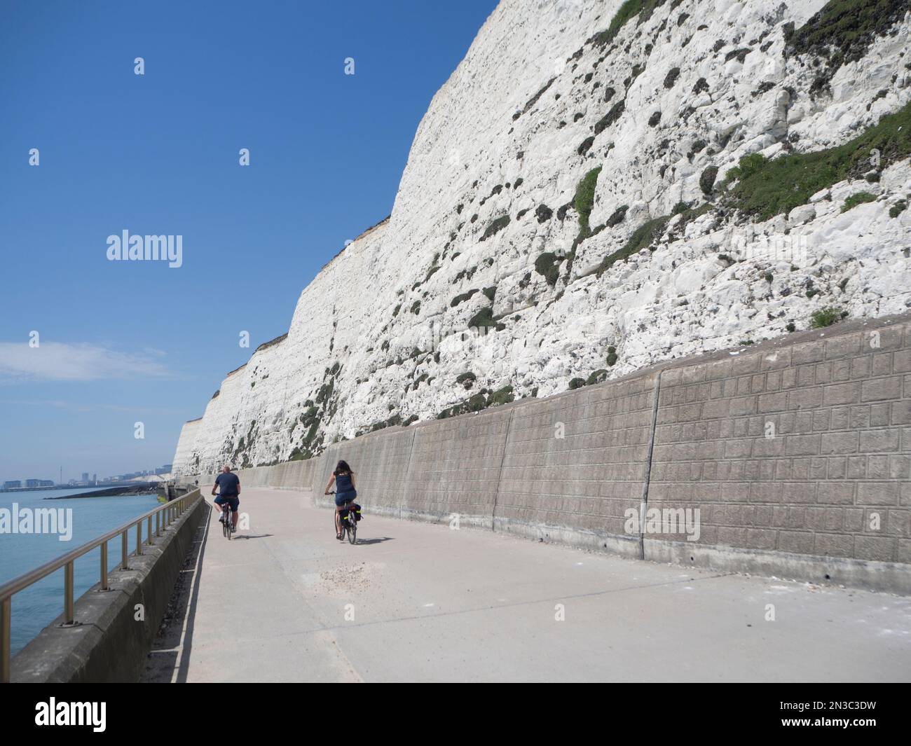 Menschen radeln entlang der weißen Kreidefelsen Promenade mit Meer; Brighton, East Sussex, England, Großbritannien Stockfoto