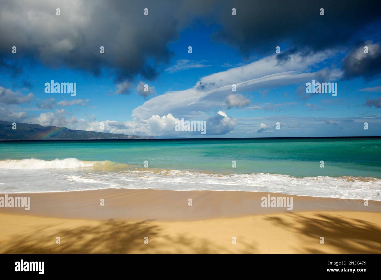 Mischung aus Regenwolken und Cumulus Wolken über dem tropischen, türkisfarbenen Wasser und ruhigen Sandstrand am Baldwin Beach Stockfoto