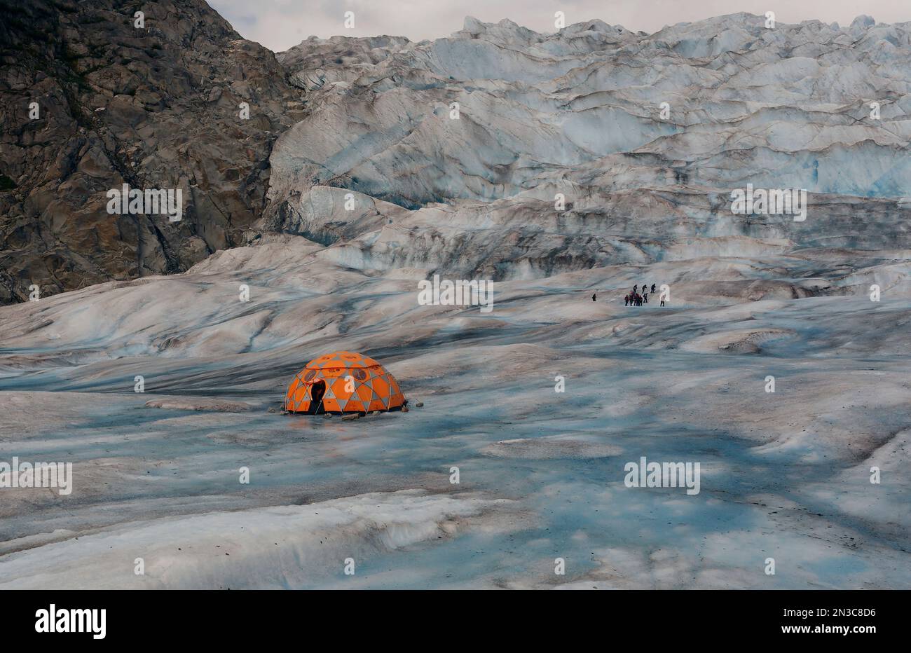 Kletterer verlassen ihr Basislager, um auf dem Eisfeld des Mendenhall-Gletschers zu wandern. Der Gletscher ist einer von vielen, die mit dem riesigen Juneau Ice Field verbunden sind... Stockfoto