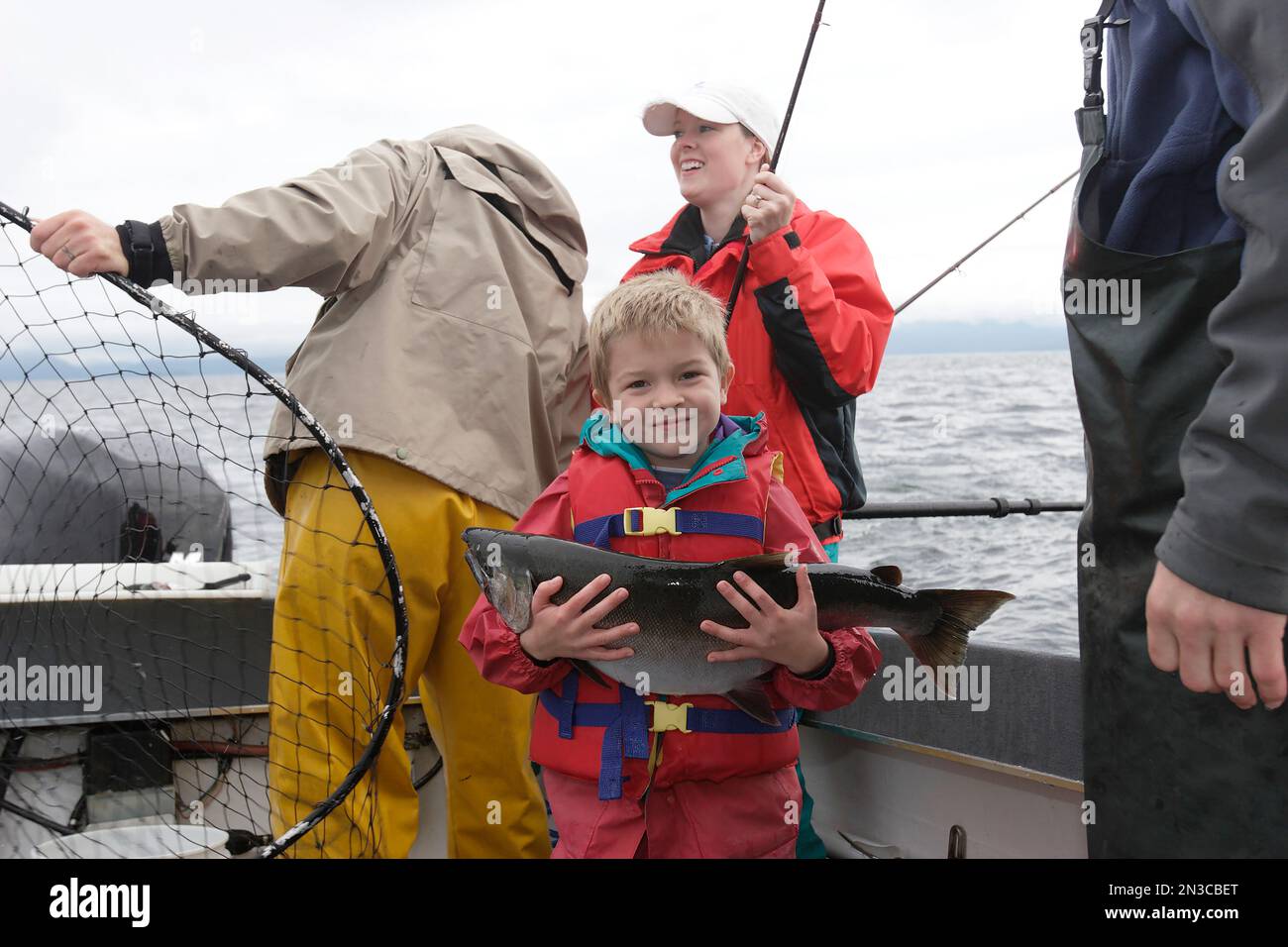 Ein Junge zeigt stolz den Lachs, den er gefangen hat, als er mit seiner Familie in der Nähe von Prince of Wales Island, Alaska, Vereinigte Staaten von Amerika, fischte Stockfoto