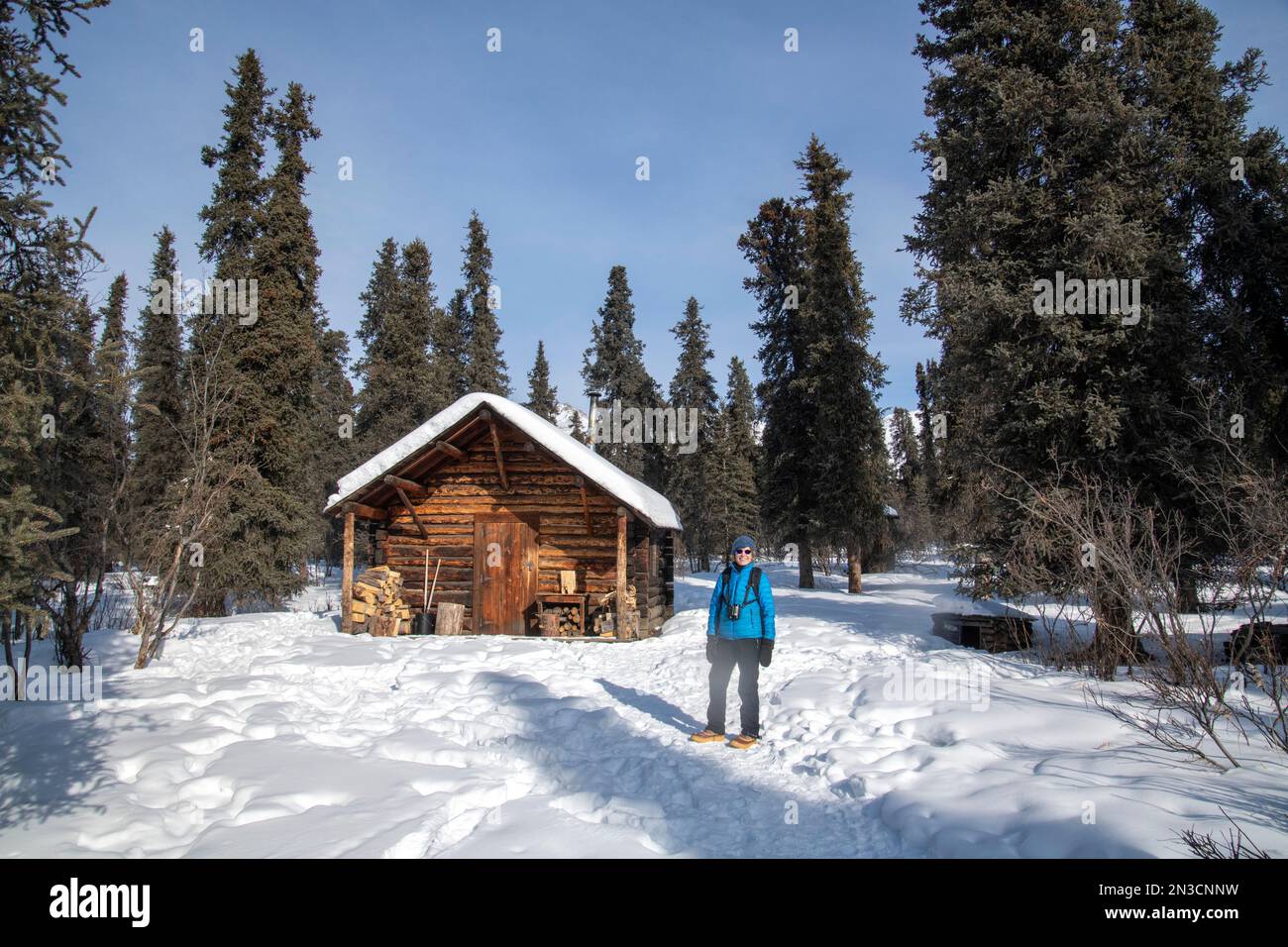 Weibliche Touristen in der historischen Savage Cabin im Winter; Denali National Park, Alaska, Vereinigte Staaten von Amerika Stockfoto