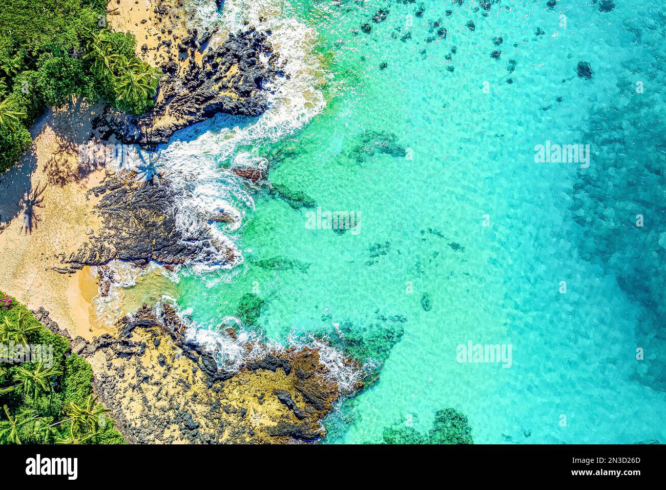 Blick direkt über der Küste und Surfen mit türkisfarbenem Wasser und Palmen am Strand der tropischen Insel Maui, Hawaii, USA Stockfoto