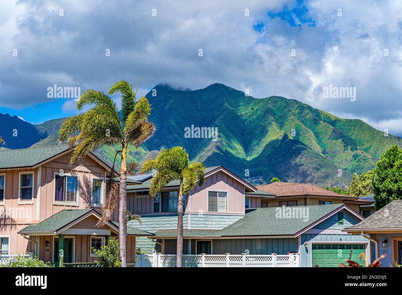 Nahaufnahme von Wohnhäusern in der Stadt Kahului, in Pastelltönen mit den dramatischen West Maui Mountains im Hintergrund Stockfoto