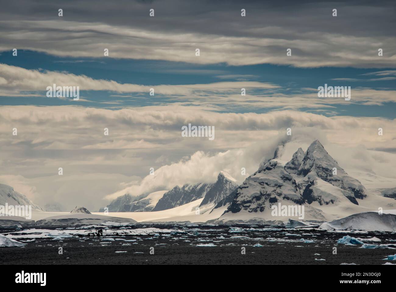 Bergige, schneebedeckte Landschaft auf Booth Island entlang der vereisten Küste des Ozeans, Heimat der Kolonien Gentoo, Adelie und Chinstrap Pinguine Stockfoto