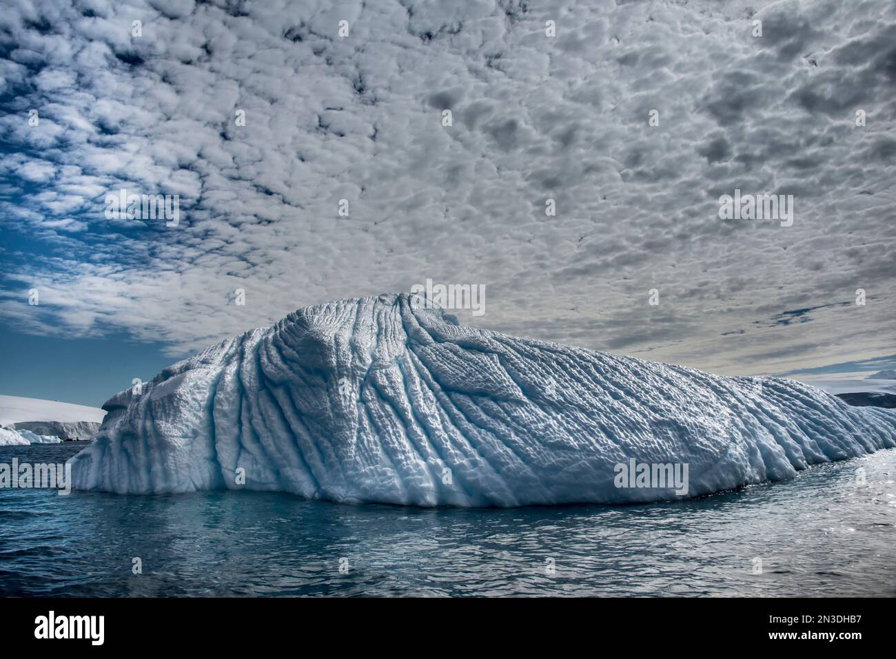 Hohe Wolken über einem Eisberg vor der Enterprise-Insel der Antarktis; Antarktis Stockfoto