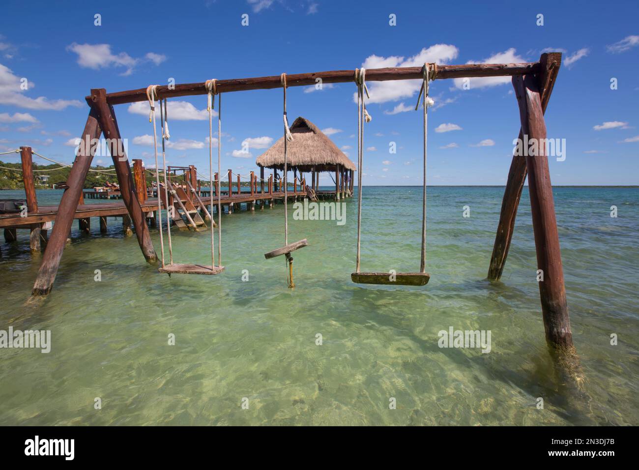 Schaukelset und Tiki Hut Pavillon am Dock mit türkisfarbenem Wasser im Rancho Encantado Eco-Resort & Spa in Bacalar; Quintana Roo, Mexiko Stockfoto