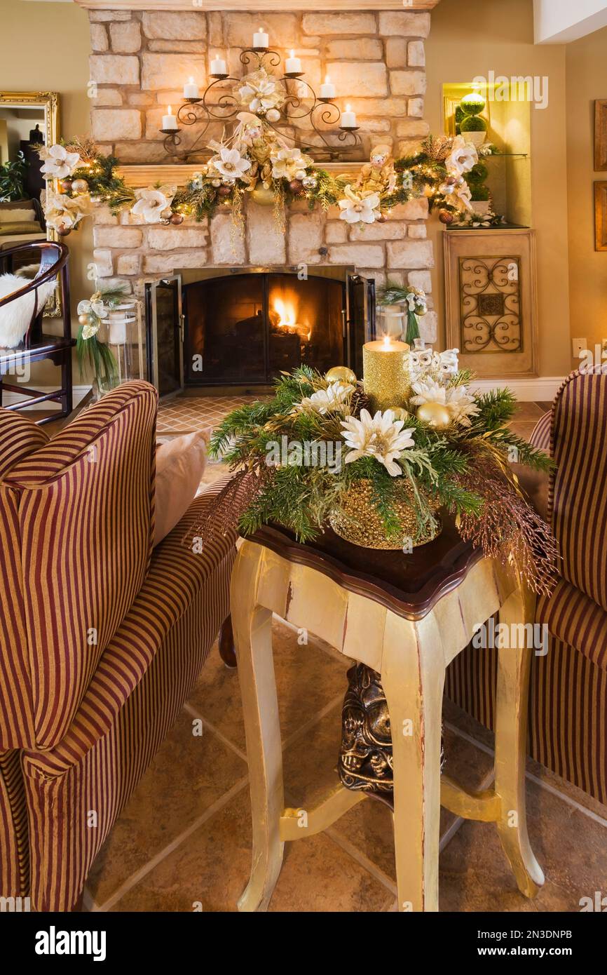 Zwei gepolsterte Sessel vor dem Kamin aus Natursteinholz mit Weihnachtsdekoration im Wohnzimmer. Stockfoto