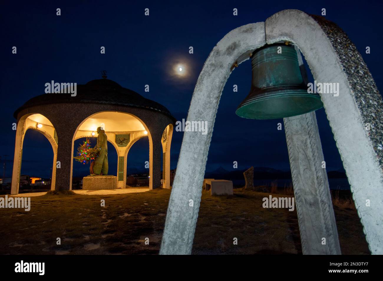 Kuppelstruktur und Statue des Seefahrer's Memorial zusammen mit einer separaten Messingglocke und Weihnachtslichtern, beleuchtet in der Abenddämmerung Stockfoto Kuppelstruktur und Statue des Seefahrer's Memorial zusammen mit einer separaten Messingglocke und Weihnachtslichtern, beleuchtet in der Abenddämmerung Stockfoto
