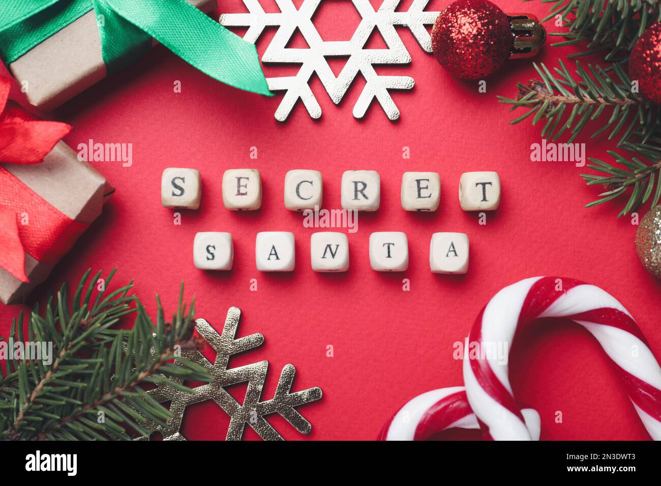 Flach liegend mit festlichem Dekor, Geschenken und Wörtern „geheimer Weihnachtsmann“ auf rotem Hintergrund Stockfoto