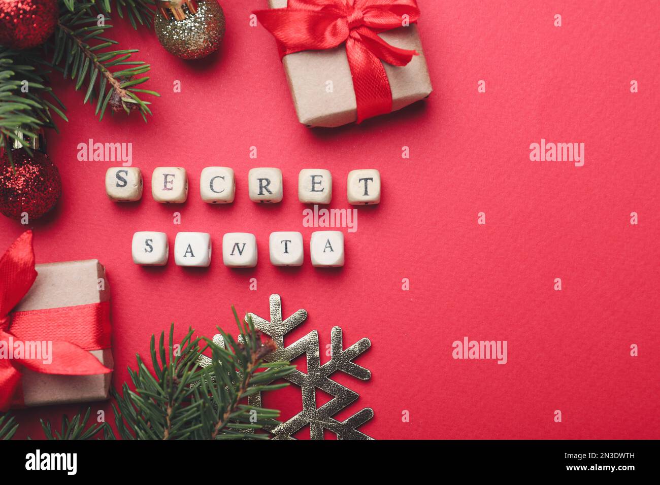 Flache Laiengestaltung mit festlicher Einrichtung, Geschenken und Wörtern „geheimer Weihnachtsmann“ auf rotem Hintergrund, Platz für Text Stockfoto