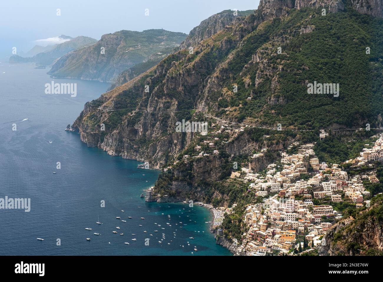 Aus der Vogelperspektive der Stadt Positano an den Klippen mit Booten, die entlang der Amalfiküste angelegt sind, und Blick in Richtung Capri; Positano, Salerno, Italien Stockfoto