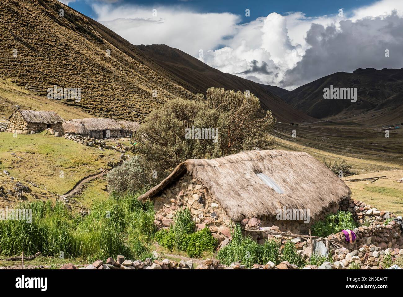Bauerngemeinde im Lares-Tal mit den Anden über den Steinhäusern mit Strohdächern; Lares-Tal, Cusco, Peru Stockfoto
