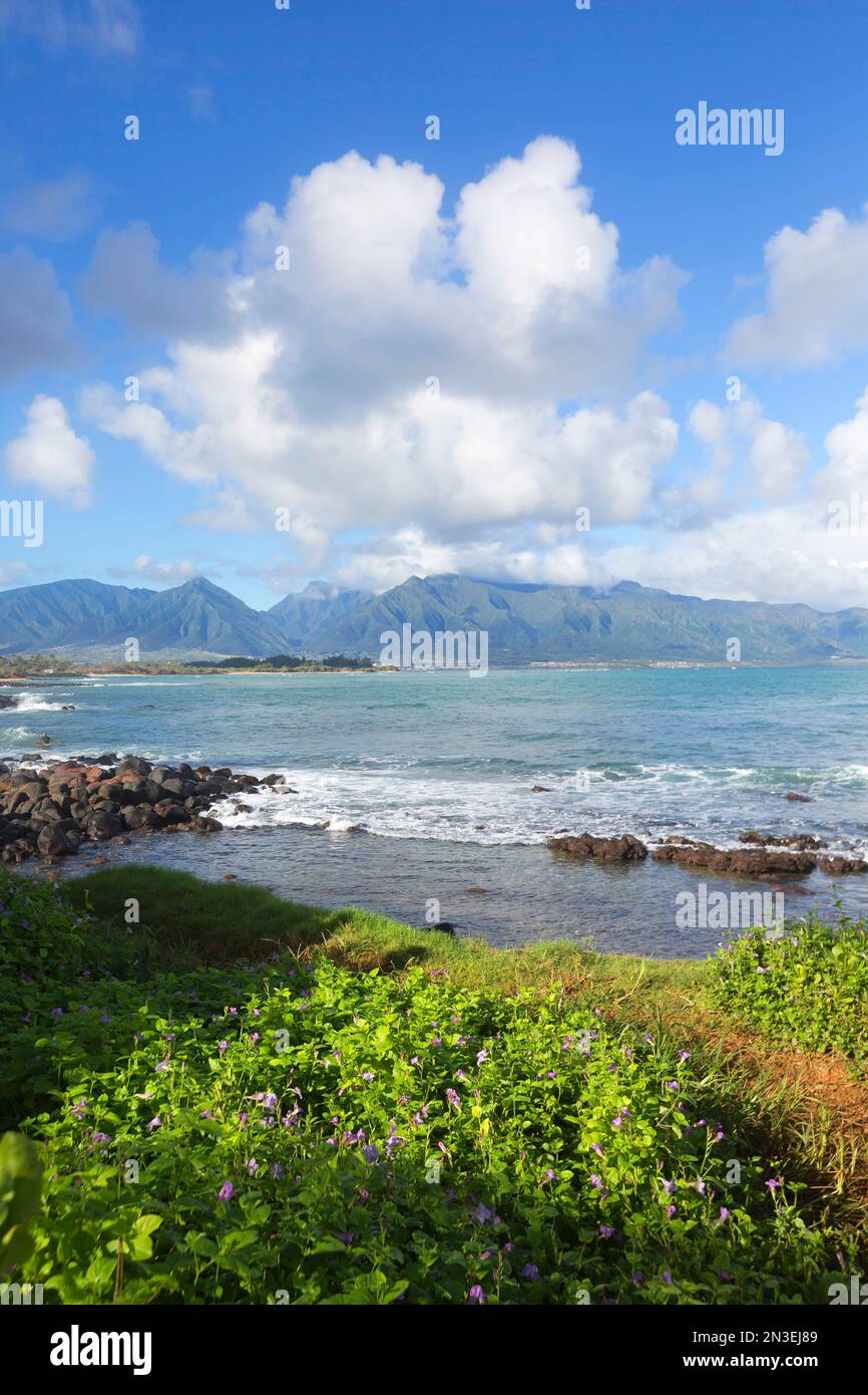 Blick auf die West Maui Mountains vom Nordufer Mauis mit dem türkisfarbenen Wasser des Pazifischen Ozeans und weißen geschwollenen Wolken in einem blauen Himmel Stockfoto