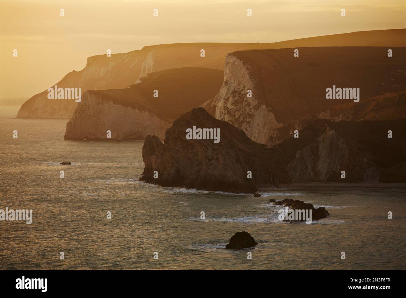 Kreidefelsen rund um Durdle Door, entlang der Jurassic Coast Weltkulturerbestätte bei Sonnenuntergang, Dorset, Großbritannien; Dorset, England Stockfoto