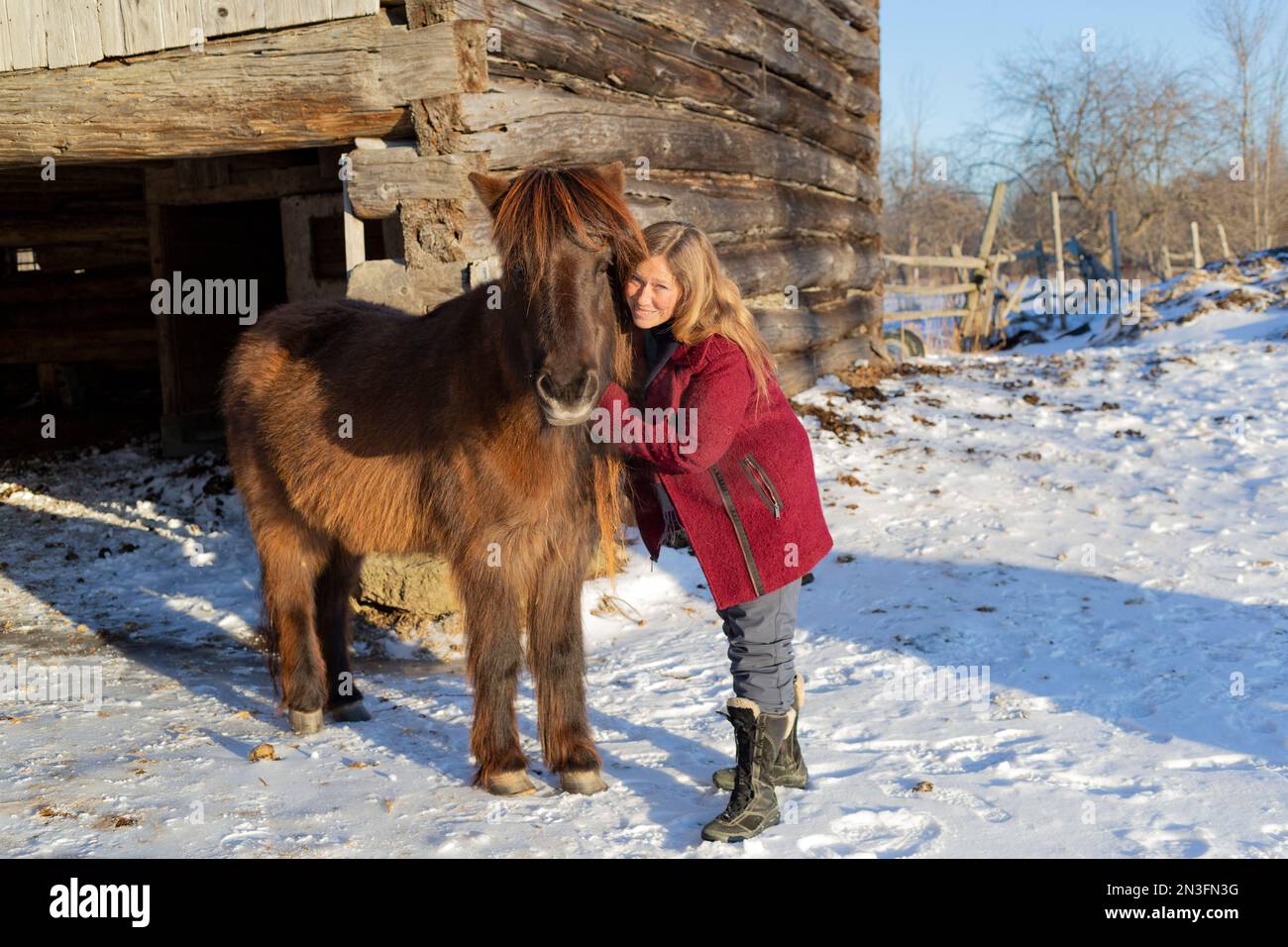 Reife Frau posiert im Winter mit einem Pferd auf einer Farm; Ottawa Valley, Ontario, Kanada Stockfoto