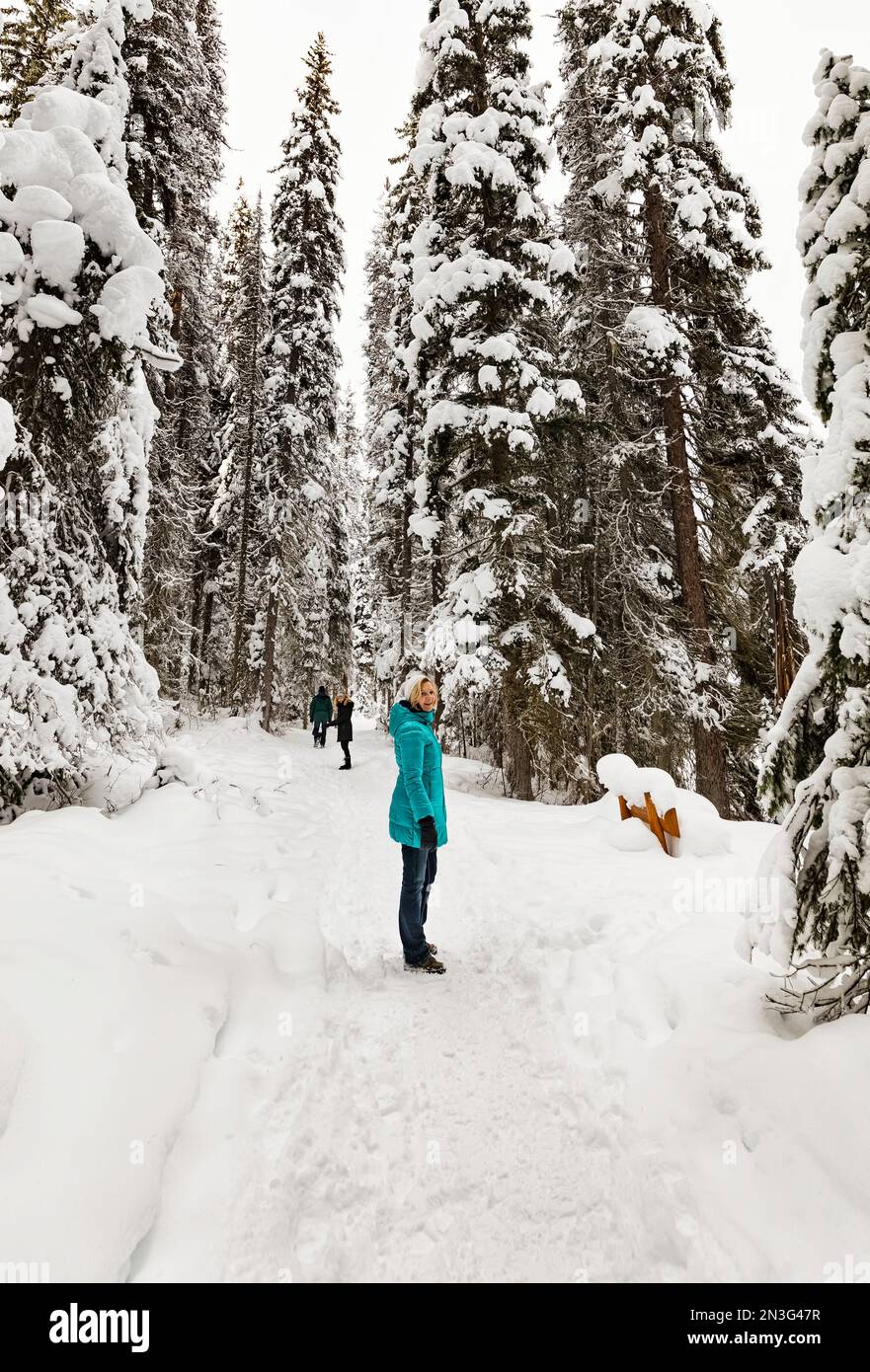 Im Winter im Yoho National Park blickt die Wanderer auf einem schneebedeckten Wanderweg rund um den Emerald Lake zurück in die Kamera Stockfoto