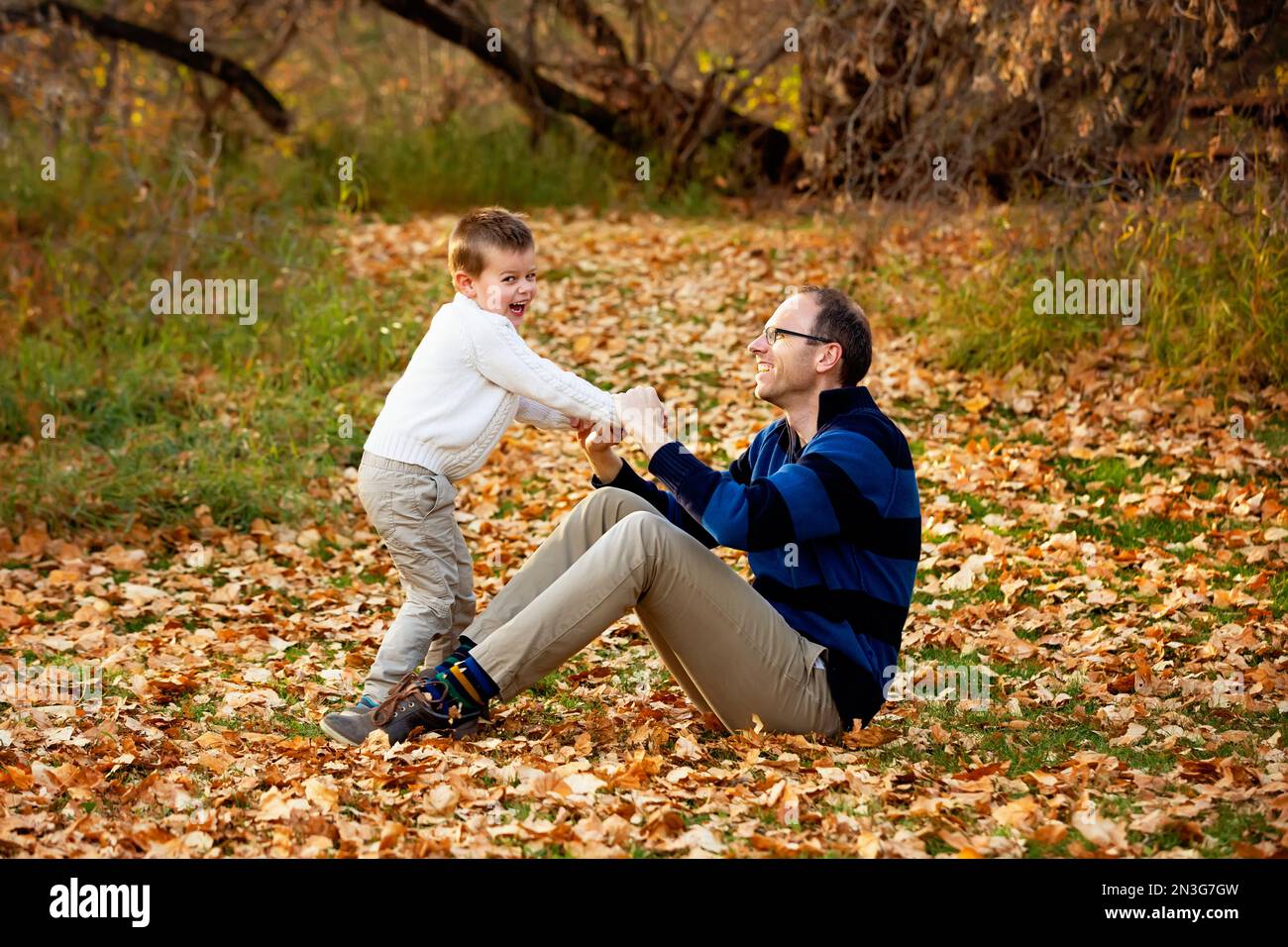 Ein Vater spielt mit seinem Sohn während eines Familienausflugs in einem Stadtpark während der Herbstsaison; St. Albert, Alberta, Kanada Stockfoto