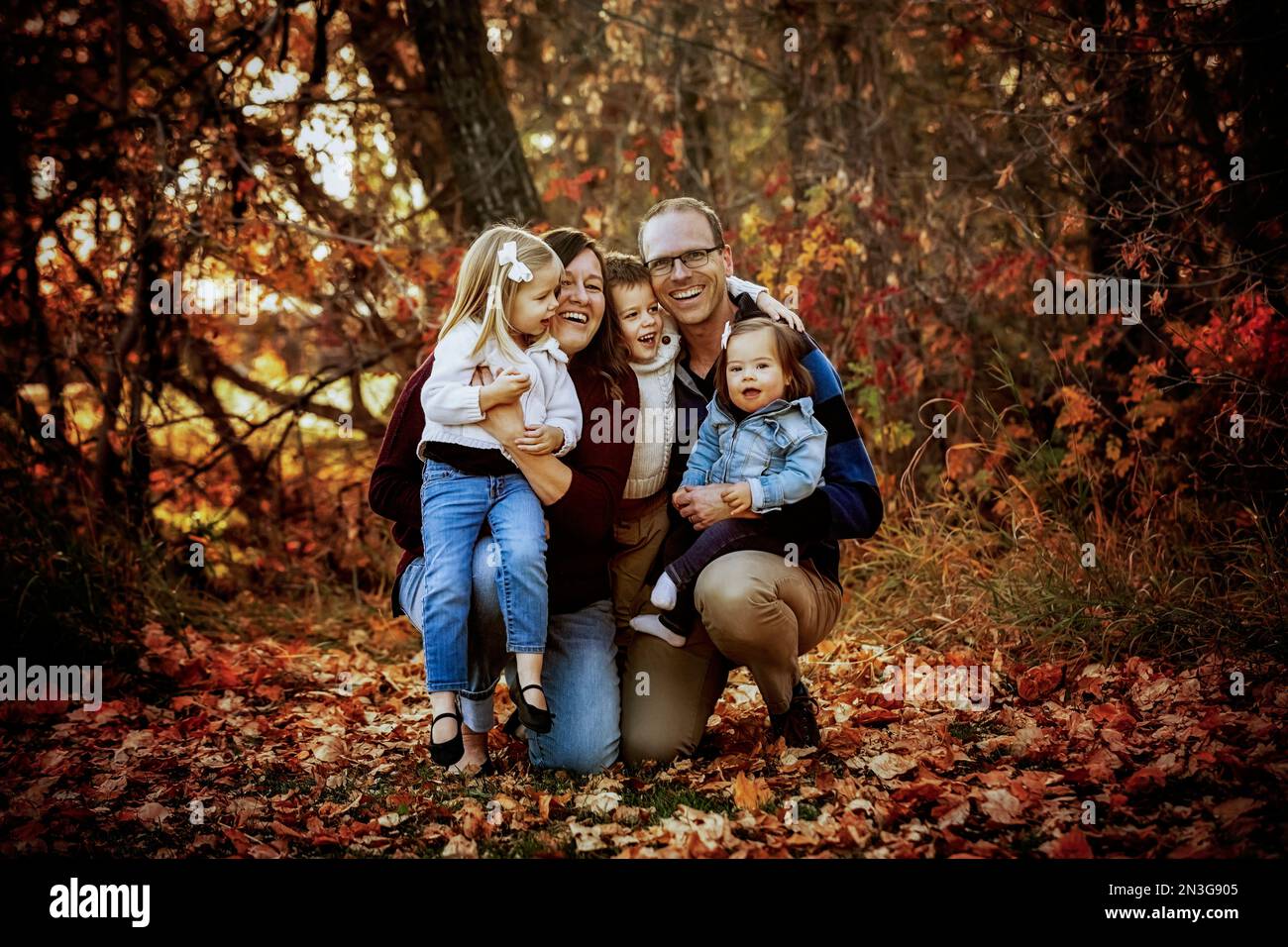 Porträt einer jungen Familie mit drei Kindern, jüngste Tochter mit Down-Syndrom, in einem Stadtpark während der Herbstsaison Stockfoto