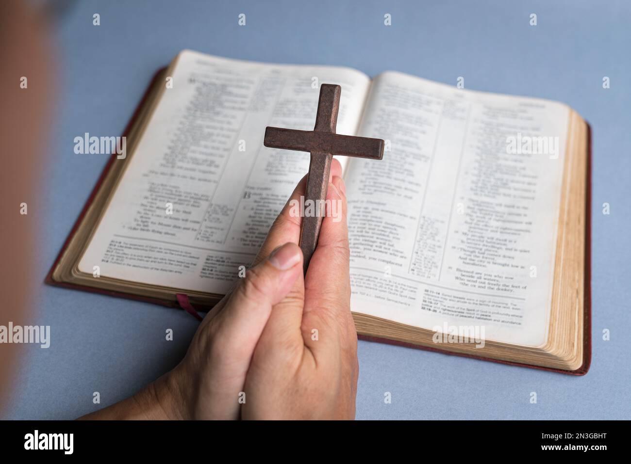 Mann, der im Hintergrund die Kreuzkreuzifx mit der offenen bibel hält. Christliches Glaubenskonzept. Stockfoto