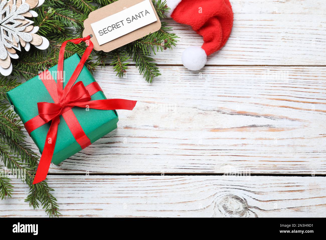 Flach liegend mit Geschenk vom geheimen Weihnachtsmann auf weißem Holztisch, Platz für Text Stockfoto