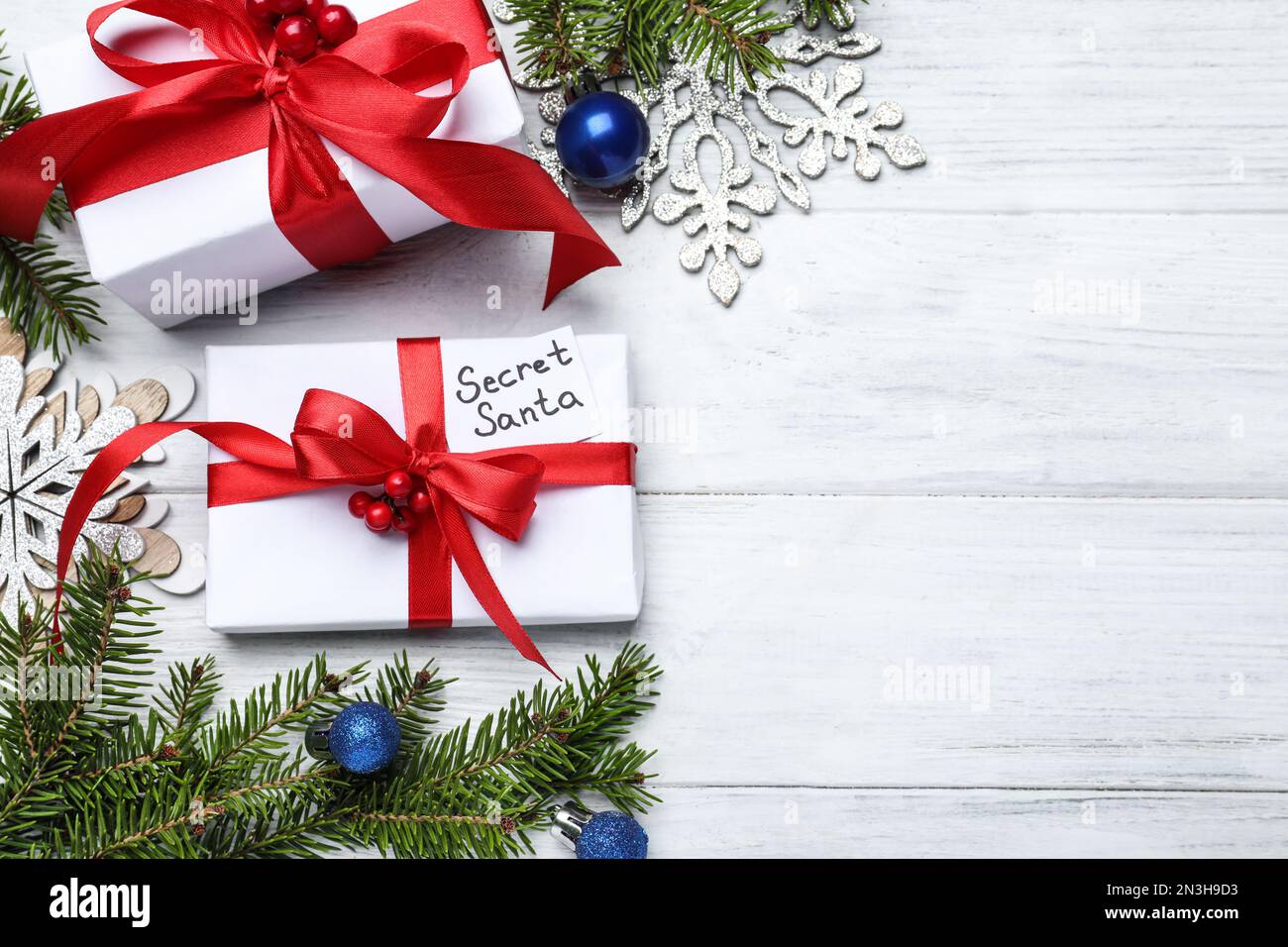 Flach liegend mit Geschenken vom geheimen Weihnachtsmann auf weißem Holztisch, Platz für Text Stockfoto