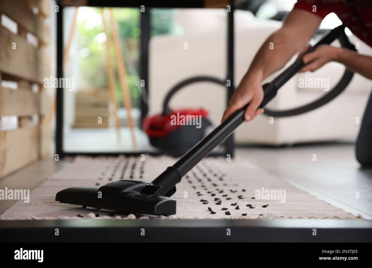 Junger Mann, der zu Hause Staubsauger benutzt, Nahaufnahme Stockfoto