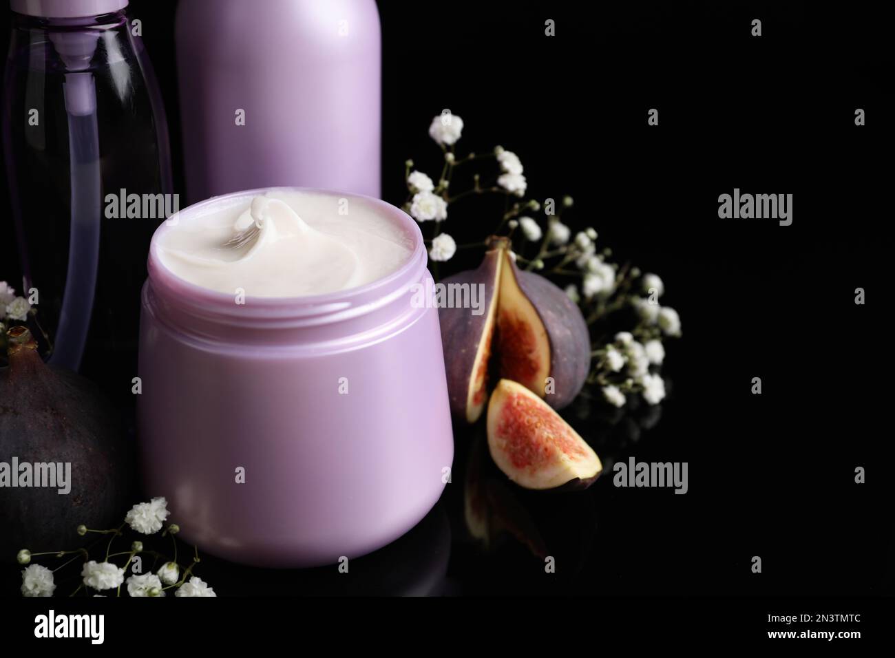 Set mit Haarkosmetika, Blumen und Feigen auf schwarzem Hintergrund, Nahaufnahme Stockfoto