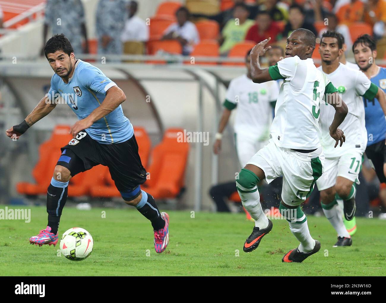 Uruguay's Luis Suarez, left, runs for the ball past Saudi Arabia's Omar Howsawi during the international friendly soccer match between Saudi Arabia and Uruguay at King Abdullah stadium in Jiddah, Saudi Arabia, Friday, Oct. 10, 2014. (AP Photo) Stockfoto