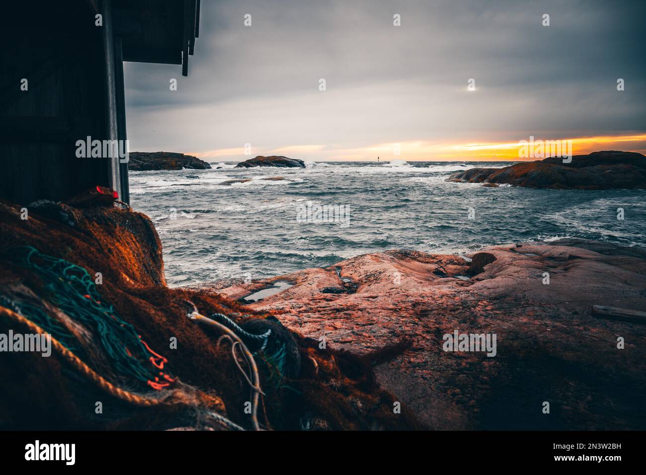 Leuchtturm im Meer, Sturm und hohe Wellen, im Vordergrund eine Hütte mit Fischernetzen, Tjurpannans Naturschutzgebiet Grebbestad, Schweden, Skandinavien Stockfoto