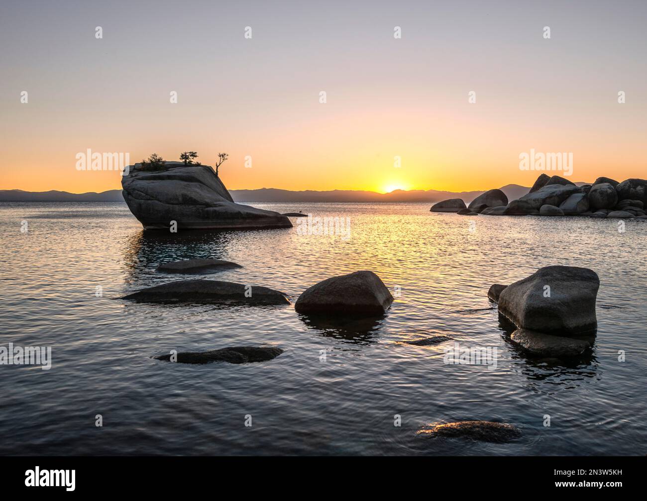 Blick auf Bonsai Rock, kleiner Baum auf einem Felsen im Wasser bei Sonnenuntergang, runde Steine im Wasser, Lake Tahoe, Kalifornien, USA Stockfoto