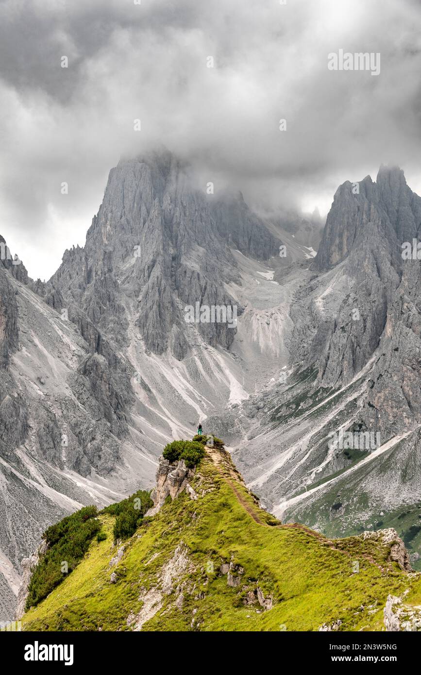Wanderer stehen auf einem Kamm, Berggipfel und spitzen Felsen dahinter, dramatisch bewölkter Himmel, Cimon di Croda Liscia und Cadini Gruppe, Auronzo di Cadore Stockfoto