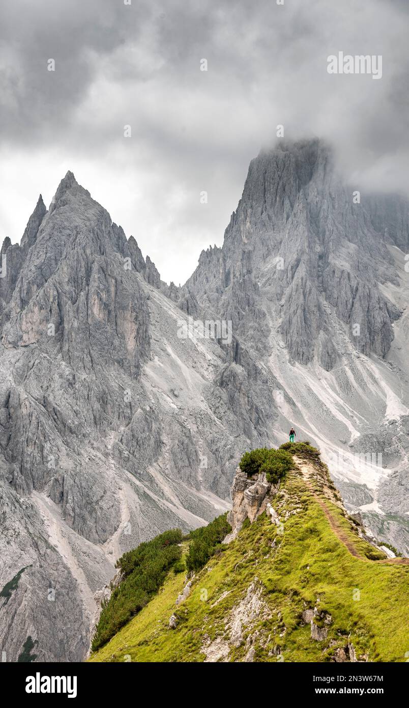 Wanderer stehen auf einem Kamm, Berggipfel und spitzen Felsen dahinter, dramatisch bewölkter Himmel, Cimon di Croda Liscia und Cadini Gruppe, Auronzo di Cadore Stockfoto
