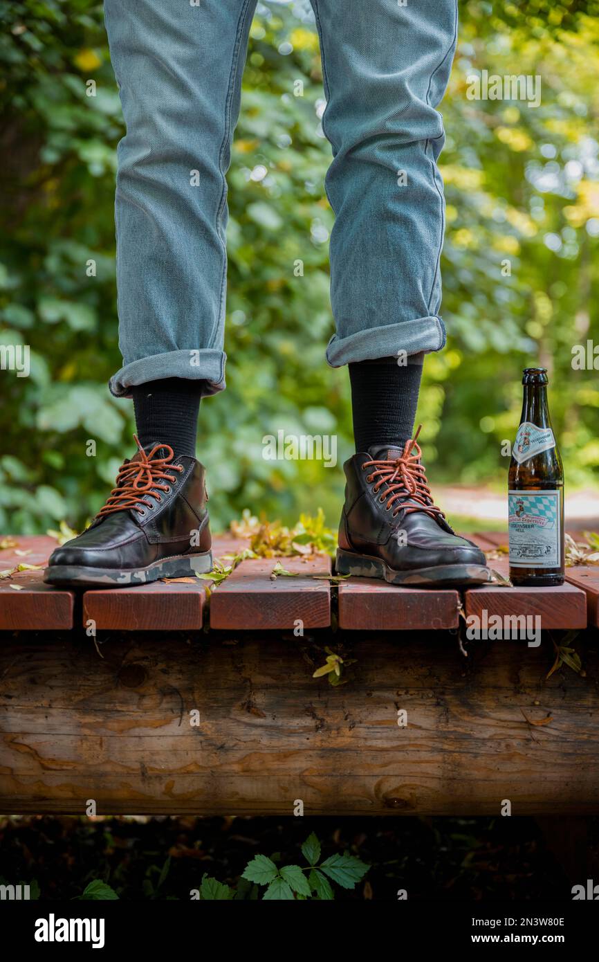 Bein mit schwarzen Schuhen und Jeans, Bierflasche, Hipster, Deutschland Stockfoto