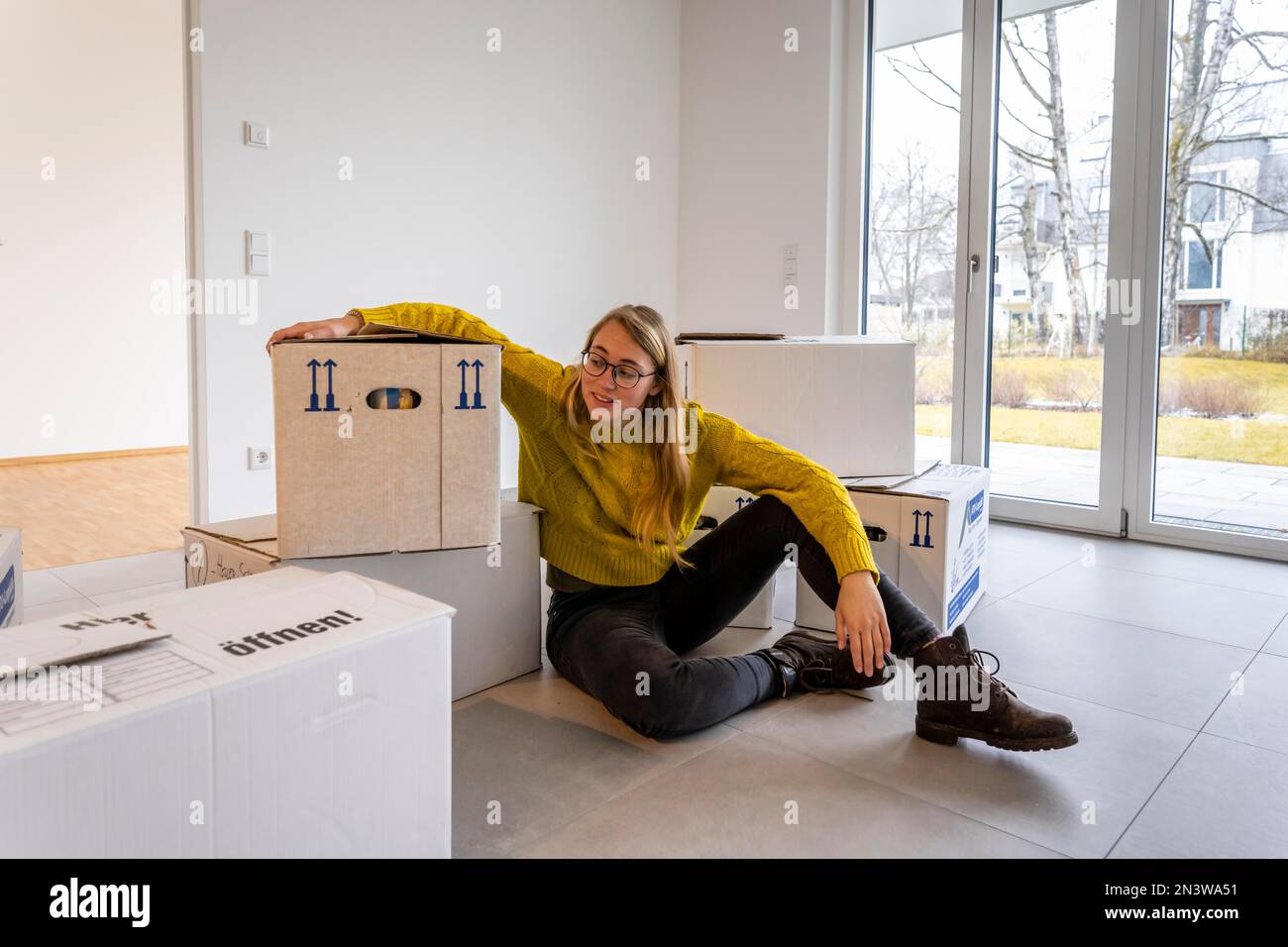 Die junge Frau zieht in eine leere Wohnung, in Deutschland Stockfoto