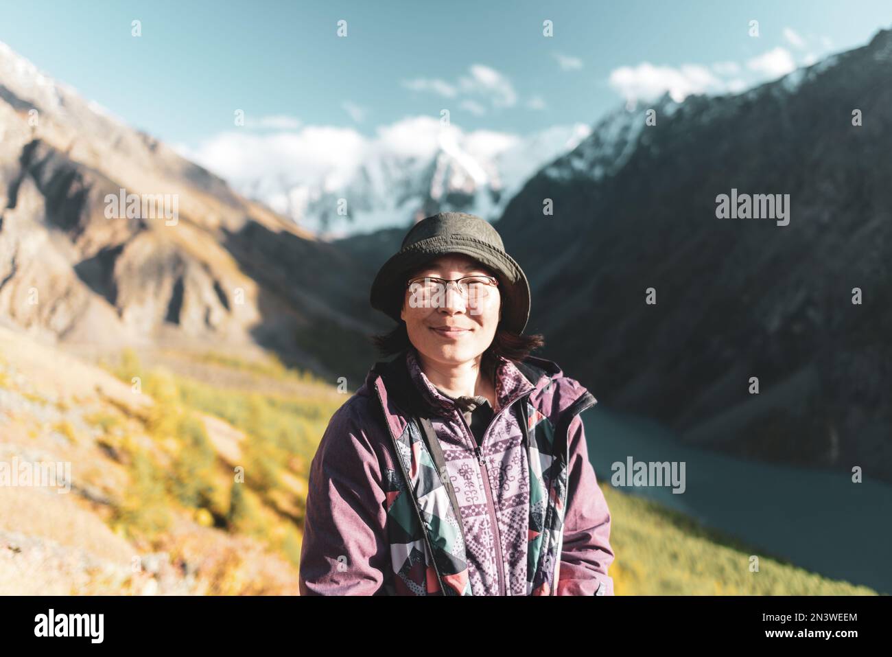 Porträt einer asiatischen Reisenden mit Hut und Brille vor dem Hintergrund einer Schlucht mit einem Bergsee Shavlinskoye im Schatten der Berge Stockfoto