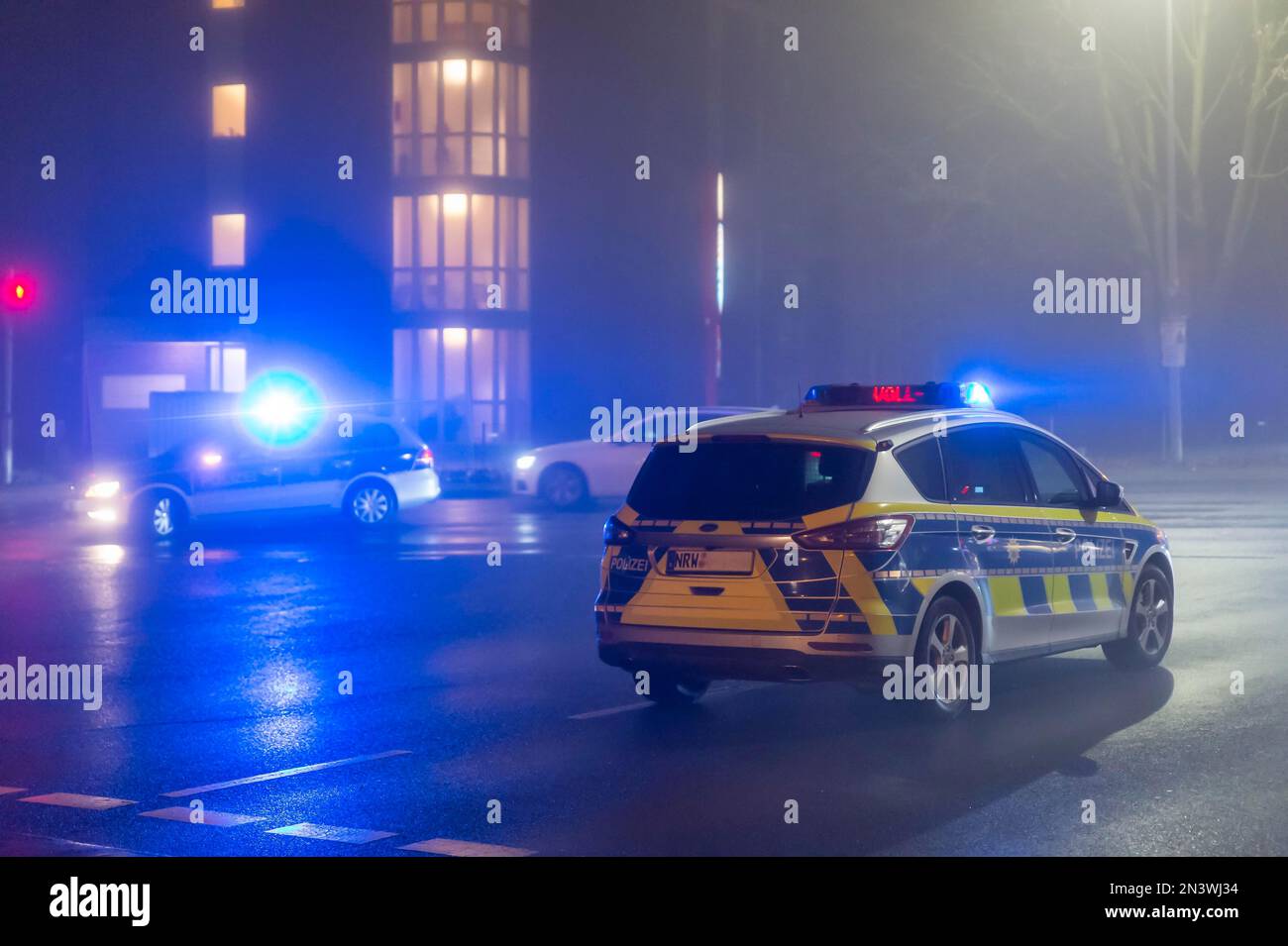 Zwei Polizeifahrzeuge an einer Kreuzung bei Nacht, Deutschland, Nordrhein-Westfalen, Grevenbroich Stockfoto