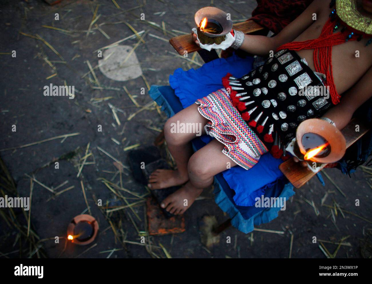 In this Wednesday, Oct. 3, 2014 photo, a young Nepalese Hindu devotee sits in a chair holding burning oil lamps as part of rituals to celebrate the tenth and final day of Dashain festival at Bhaktapur, also known as the city of devotees, in Katmandu, Nepal. The festival commemorates the slaying of a demon king by Hindu goddess Durga, marking the victory of good over evil. (AP Photo/Niranjan Shrestha) Stockfoto