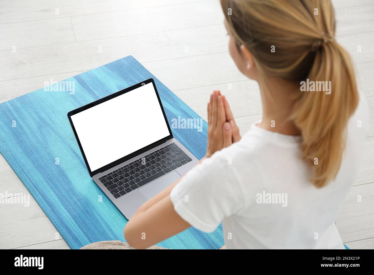 Frau, die zu Hause einen Online-Videokurs über ein Notebook führt. Distanz-Yoga-Kurs während der Coronavirus-Pandemie Stockfoto