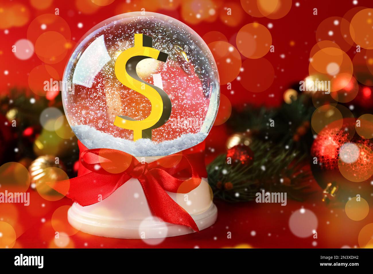 Schneekugel mit Dollarzeichen und Weihnachtsdekor auf rotem Hintergrund, Bokeh-Effekt Stockfoto