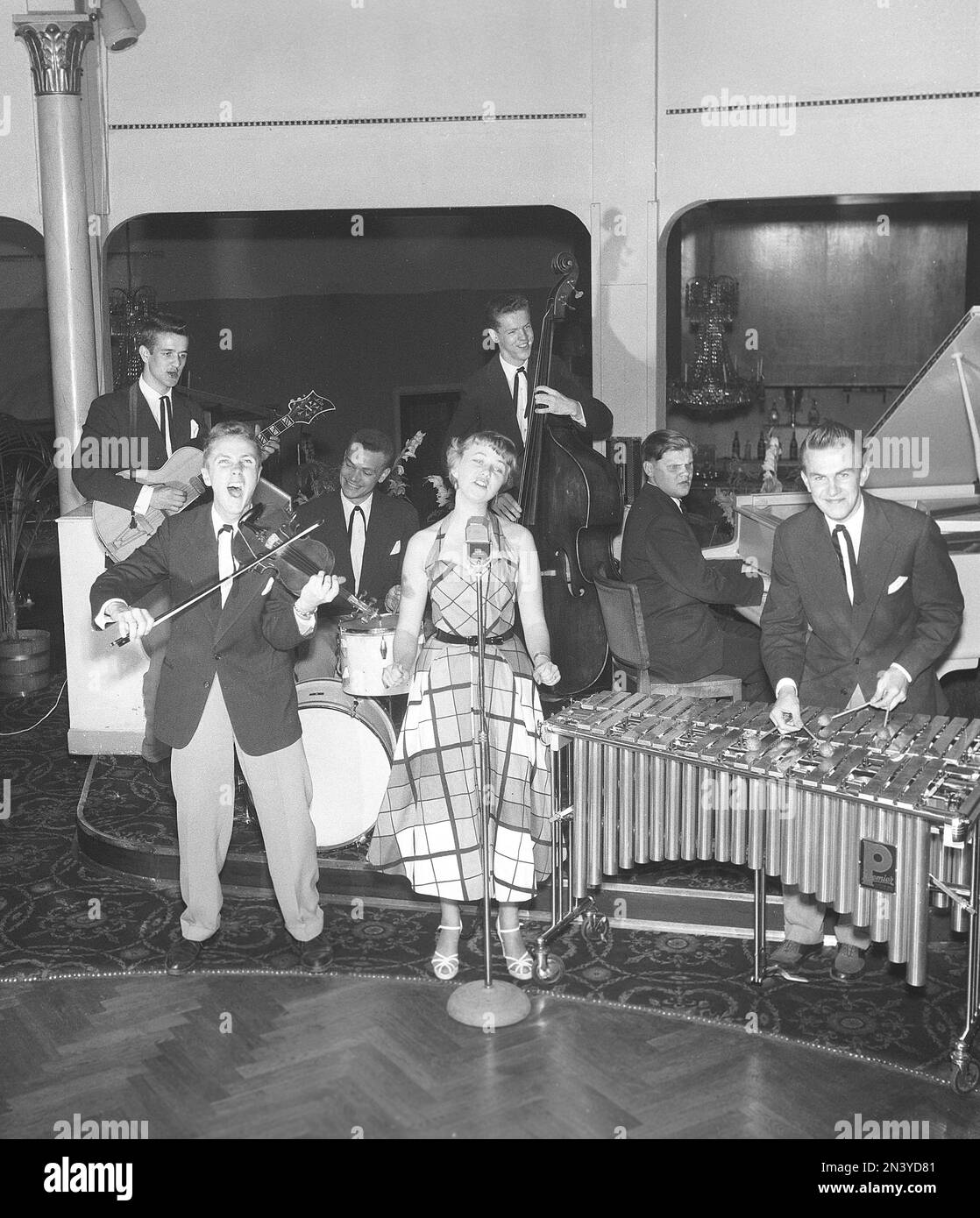 In den 1950er Jahren. Eine junge Frau sah, wie sie auf der Bühne mit einem Mikrofon vor sich sang, während ein Orchester verschiedene Musikinstrumente spielte, Gitarre, Geige, Schlagzeug, Klavier und Xylophon. Stockholm Schweden 1954 Kristoffersson Ref. BP60-5 Stockfoto